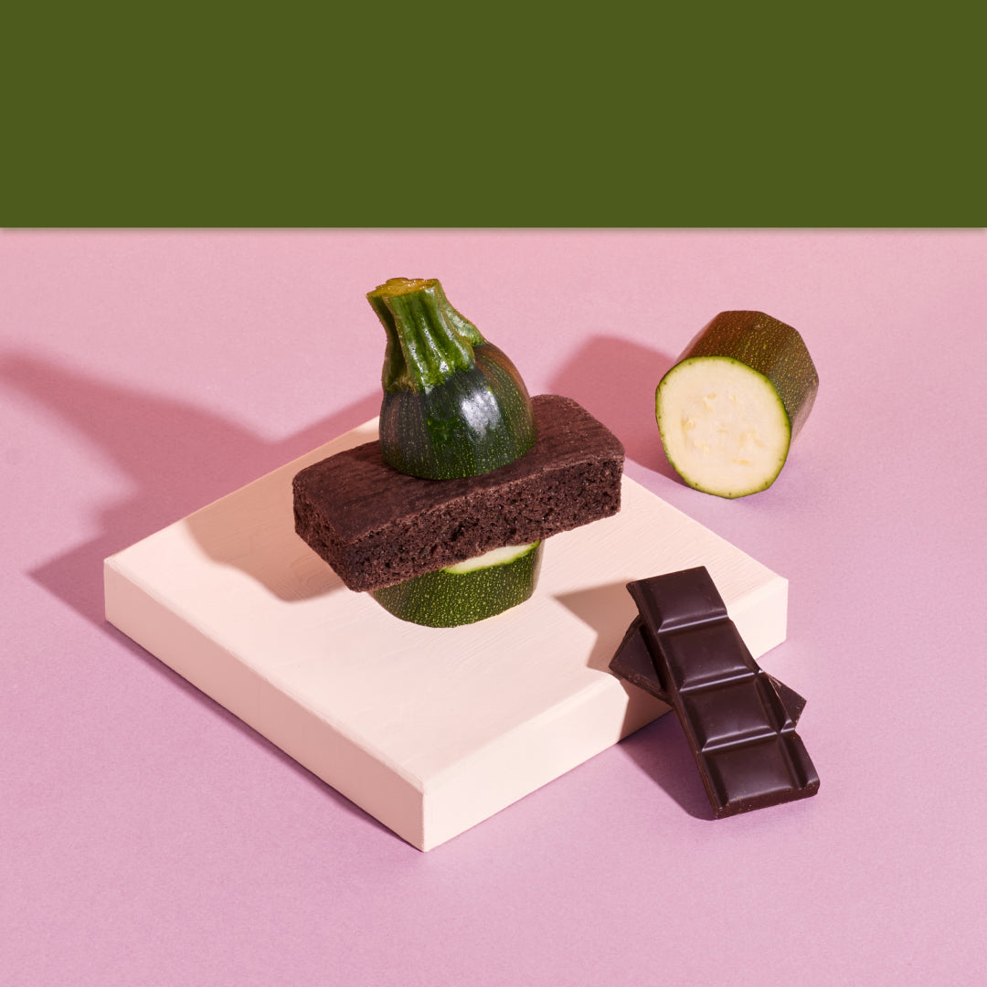 Schoko-Zucchini Kuchen in Szene gesetzt mit einem Stück Zucchini und dunkler Schokoloade